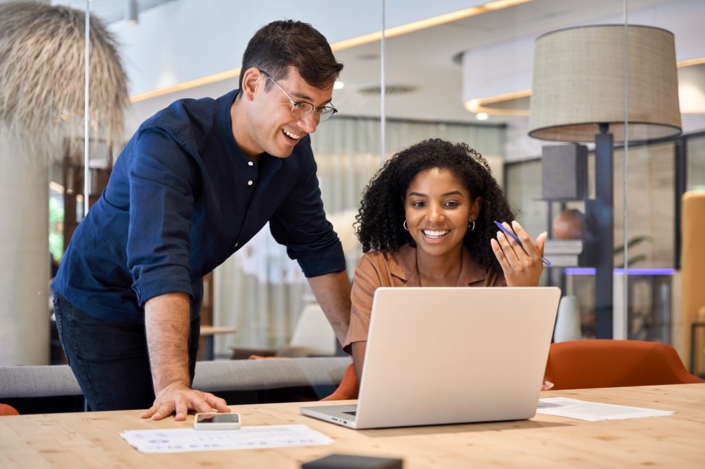 Two young busy diverse colleagues business people using laptop in modern office.